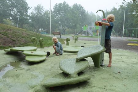 Två barn leker i vattenleken som finns i Årstaparken.